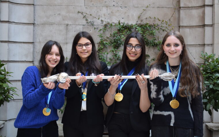 4 girls from St Paul's Girl's school who are the schools' mace debating competition winners holding the mace