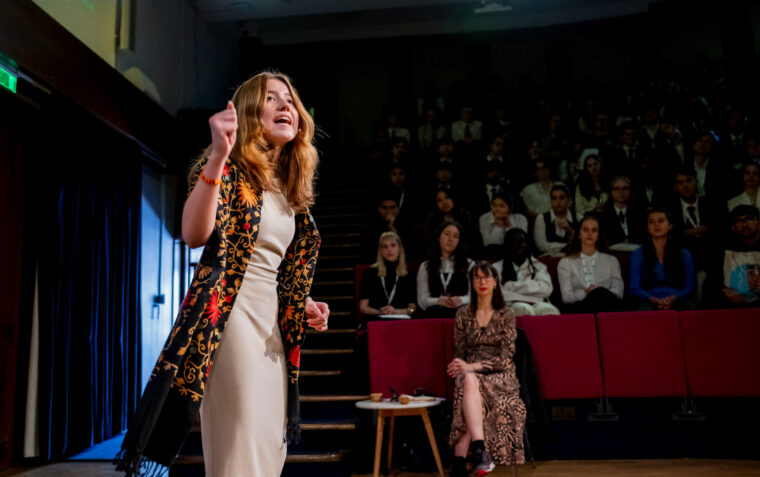 A young woman stood on a stage performing for an audience.
